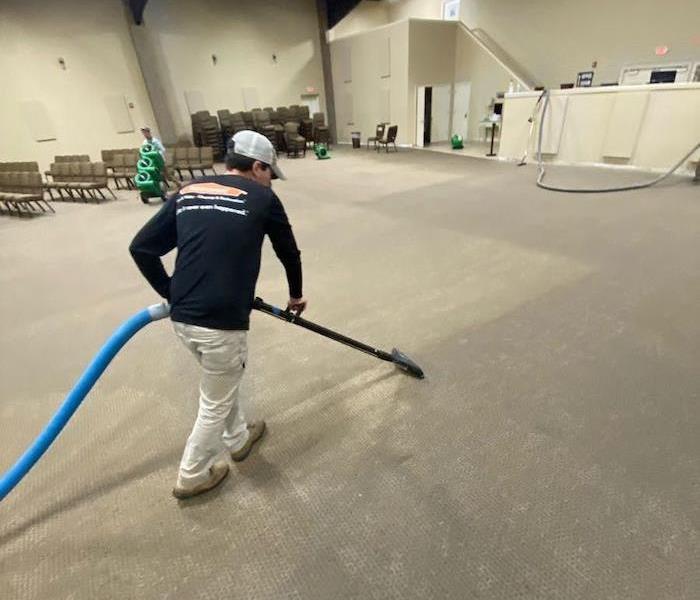 SERVPRO tech with extraction wand and wet gray carpet