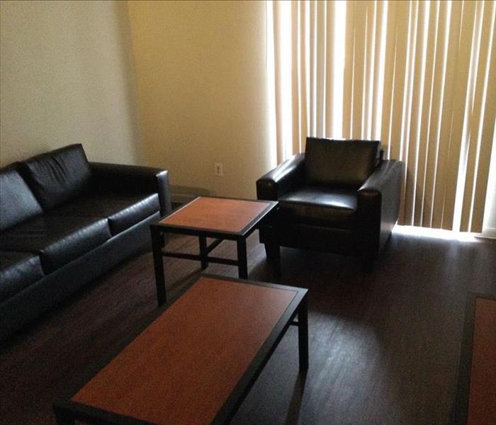Clean room with sofa and chair with tables and television