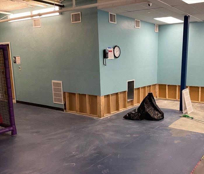 Preschool gym with flood cuts on lower drywall and exposed framing near removed flooring