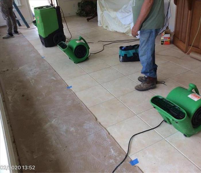 SERVPRO tech with drying equipment on the tile floor
