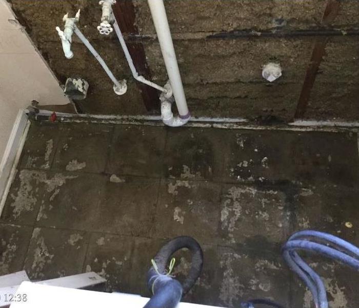 Laundry room with water damaged floor and exposed plumbing 