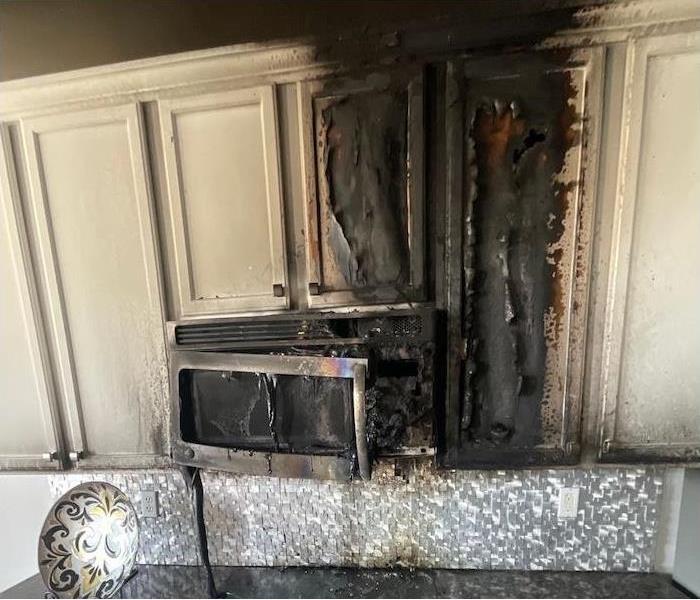 Kitchen cabinets and microwave with fire damage